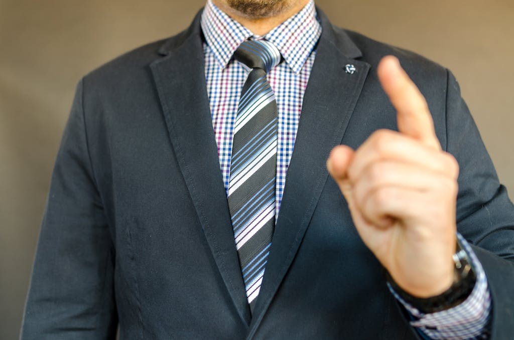 Close-up of a man in a suit making a gesture, symbolizing instruction or guidance. MBA and DBA programs online